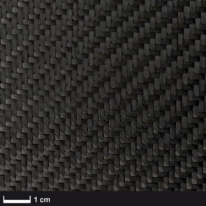 Nærbillede af Kulfibervæv, 200g, twill, 100cm - et tætvævet sort kulfiberstof med et synligt zigzag twill-mønster. En skala på 1 cm viser vævestørrelsen. Ideelt til marineprojekter. Mere info på boatkitshop.com.