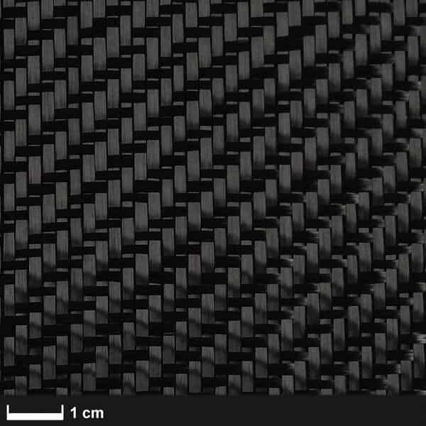 Nærbillede af Kulfibervæv, 160g, twill, 100cm viser den fine sortvævede kulfiberstruktur på kryds og tværs. En skala angiver en bredde på 1 cm - ideel til marineforsyningsprojekter. Find det på boatkitshop.com.
