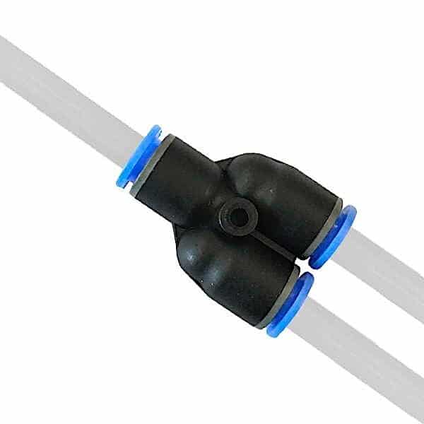 Nærbillede af en Slangetilslutning - Y-stykke plaststikforbindelse med to hvide rør indsat overfor hinanden. Det sorte stik har blå ringe i de ender, hvor rørene sidder fast.