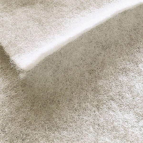 Et nærbillede af Absorber 150g, et hvidt, fibrøst polyestervat med en blød, luftig og fluffy tekstur, der fremhæver dets lette, lagdelte udseende.
